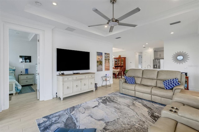 living room with a raised ceiling, light hardwood / wood-style flooring, ceiling fan, and ornamental molding