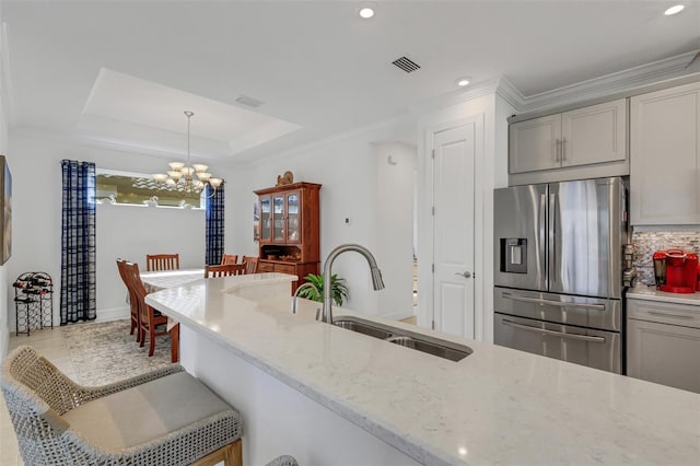 kitchen with sink, decorative light fixtures, light stone countertops, a notable chandelier, and stainless steel fridge with ice dispenser