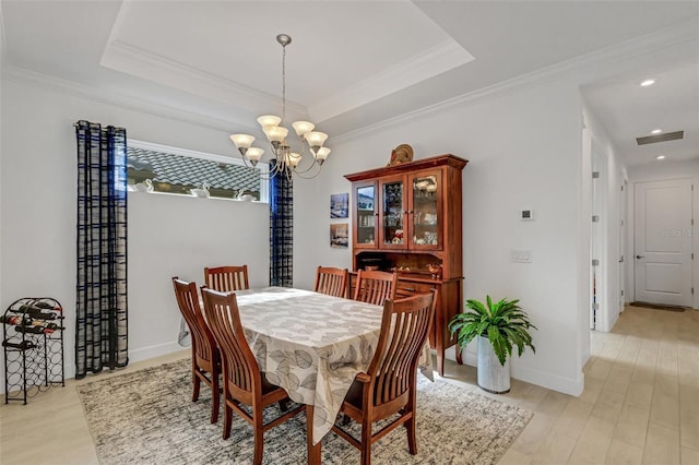 dining room with light wood-type flooring, ornamental molding, and an inviting chandelier