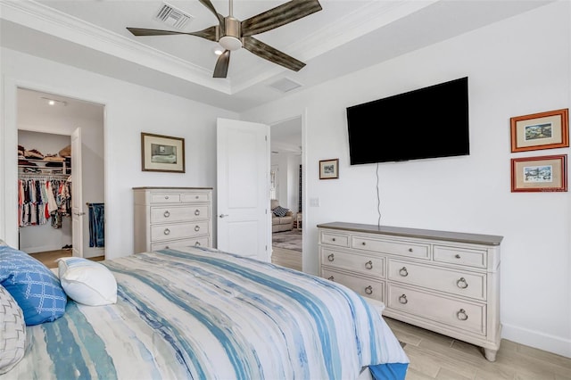 bedroom with a walk in closet, a closet, ceiling fan, and ornamental molding