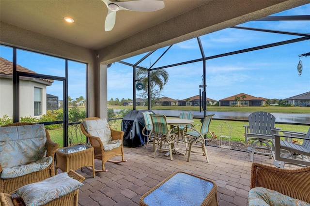 sunroom with a water view and ceiling fan