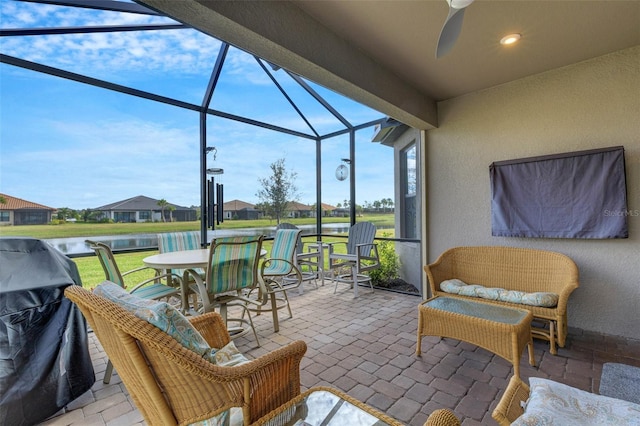 view of patio / terrace with a lanai, ceiling fan, area for grilling, and a water view