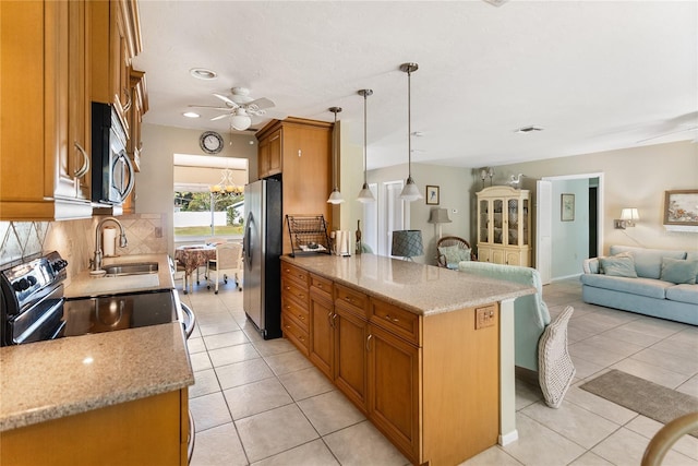 kitchen with pendant lighting, backsplash, sink, light stone countertops, and stainless steel appliances