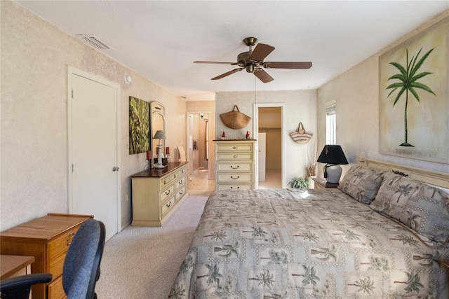 bedroom featuring light carpet, a closet, a spacious closet, and ceiling fan