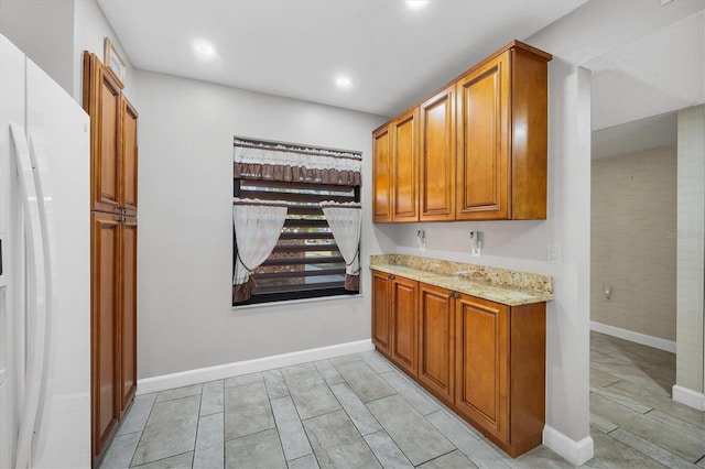 kitchen featuring white refrigerator and light stone countertops