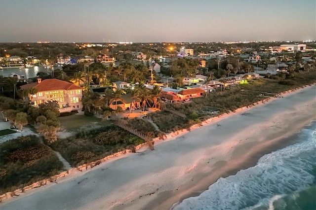 aerial view at dusk with a view of the beach and a water view