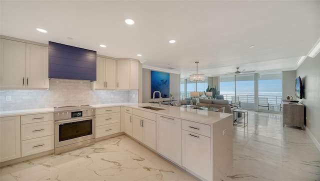 kitchen with custom exhaust hood, sink, ceiling fan, stainless steel range, and kitchen peninsula