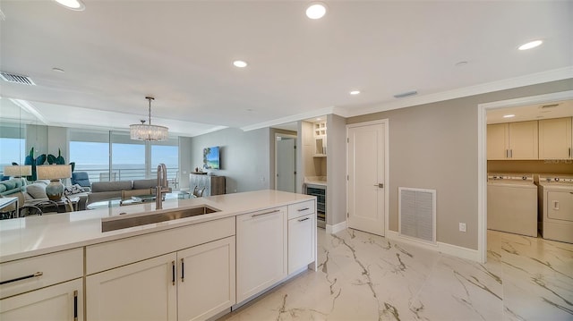 kitchen with white dishwasher, sink, hanging light fixtures, independent washer and dryer, and a chandelier