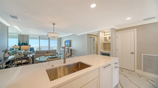 kitchen with crown molding, sink, decorative light fixtures, an inviting chandelier, and white cabinetry