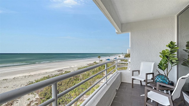 balcony with a water view and a view of the beach