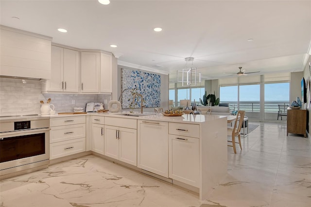 2105 Gulf Of Mexico Dr Unit 3303, Longboat Key, FL 34228 - kitchen with light marble finish floors, a peninsula, tasteful backsplash, a ceiling fan, and stainless steel oven