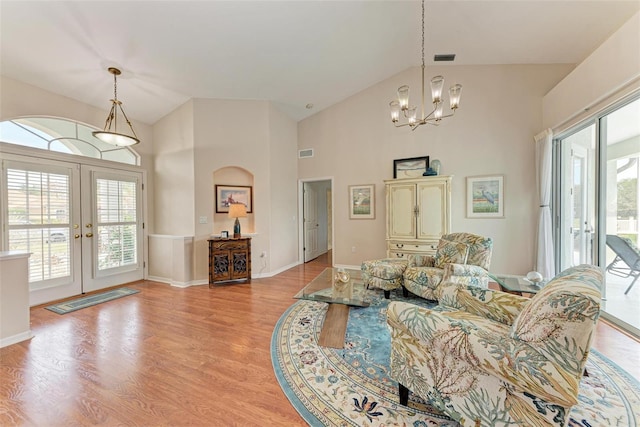 living room with french doors, high vaulted ceiling, light hardwood / wood-style flooring, and a notable chandelier