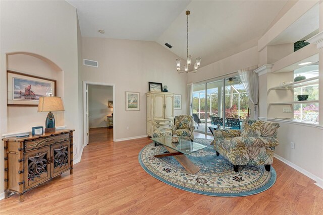 living room with light hardwood / wood-style floors, high vaulted ceiling, and a chandelier