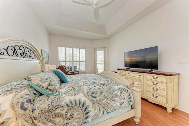 bedroom featuring light hardwood / wood-style floors, a raised ceiling, and ceiling fan