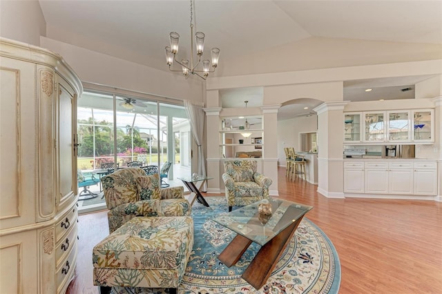 living room with decorative columns, a chandelier, vaulted ceiling, and light wood-type flooring