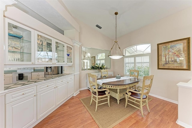 dining space featuring lofted ceiling and light hardwood / wood-style flooring