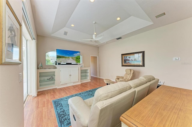 living room featuring a tray ceiling, a wealth of natural light, light hardwood / wood-style flooring, and ceiling fan