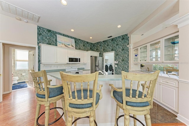 kitchen featuring white cabinetry, light wood-type flooring, white appliances, and independent washer and dryer