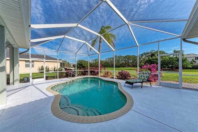 view of pool with a lawn, glass enclosure, and a patio