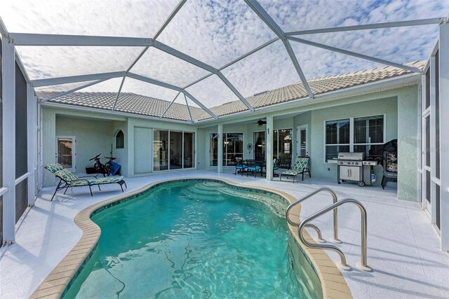 view of swimming pool featuring glass enclosure, a patio area, and ceiling fan