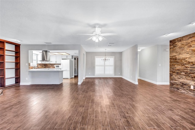 unfurnished living room with ceiling fan with notable chandelier, dark wood-type flooring, and a textured ceiling