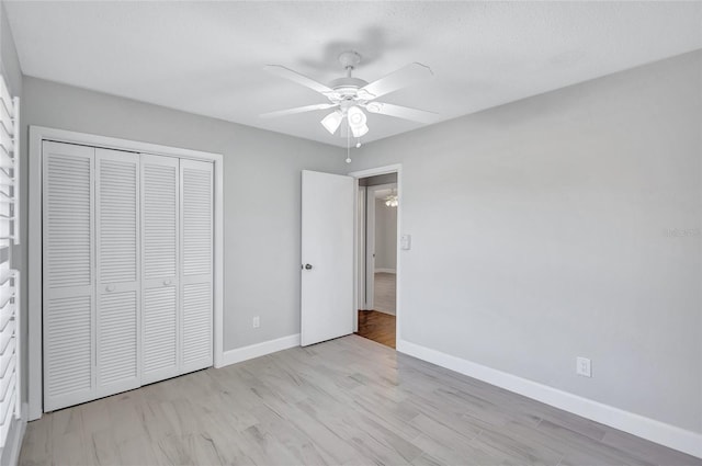 unfurnished bedroom with ceiling fan, light wood-type flooring, and a closet