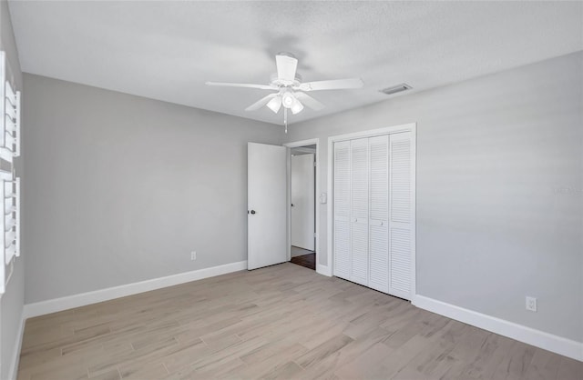 unfurnished bedroom with ceiling fan, light hardwood / wood-style floors, a textured ceiling, and a closet