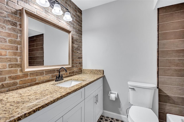 bathroom with vanity, brick wall, and toilet