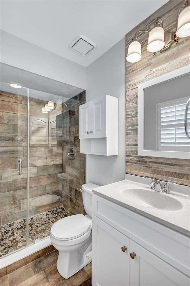 bathroom featuring vanity, hardwood / wood-style flooring, toilet, and a shower with shower door