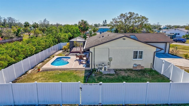 back of property featuring a yard, a patio, and a fenced in pool