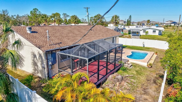 rear view of property featuring a fenced in pool, glass enclosure, a patio area, and a lawn