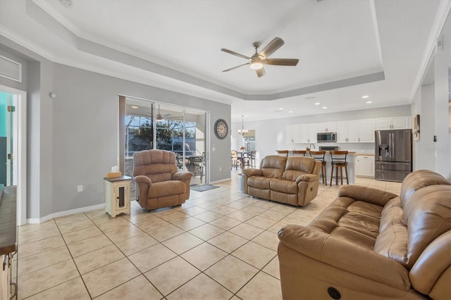 living room featuring ceiling fan, a raised ceiling, light tile patterned floors, and crown molding