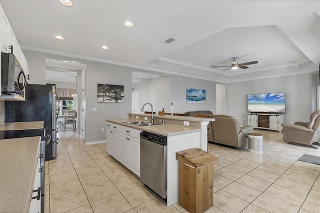 kitchen featuring sink, white cabinets, stainless steel appliances, and a center island with sink