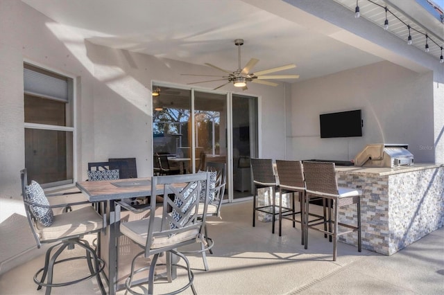 view of patio featuring ceiling fan, exterior bar, and an outdoor kitchen