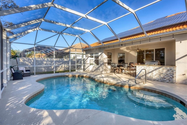 view of pool featuring glass enclosure, ceiling fan, an outdoor kitchen, an outdoor bar, and a patio