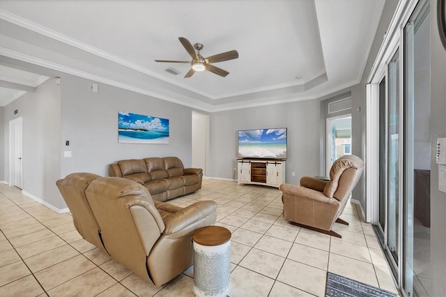 living area featuring light tile patterned flooring, visible vents, baseboards, a raised ceiling, and crown molding