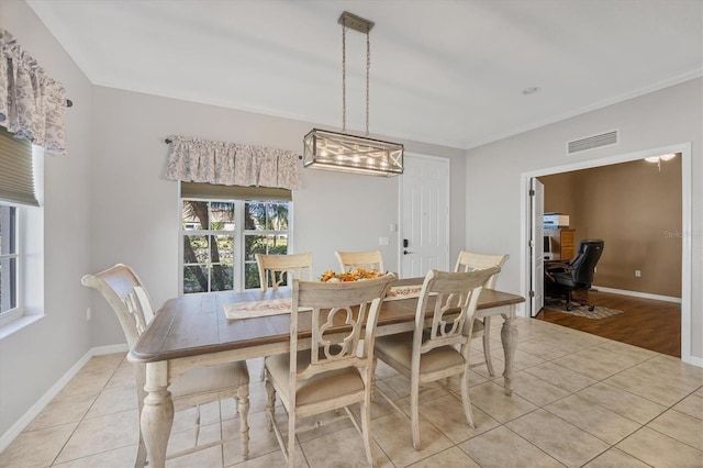 dining area with light tile patterned floors, crown molding, visible vents, and baseboards