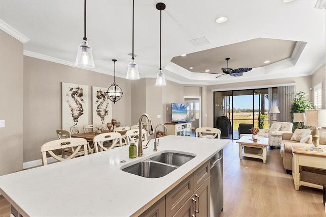 kitchen featuring ornamental molding, ceiling fan, sink, a center island with sink, and hanging light fixtures