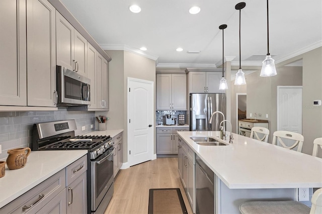 11265 Mc Dermott Ct, Englewood, FL 34223 - kitchen featuring appliances with stainless steel finishes, a kitchen breakfast bar, gray cabinets, ornamental molding, and light wood finished floors