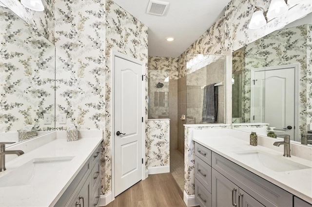 bathroom with a tile shower, vanity, and hardwood / wood-style flooring