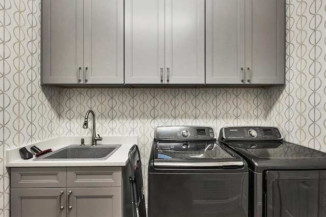 clothes washing area with sink, cabinets, and independent washer and dryer