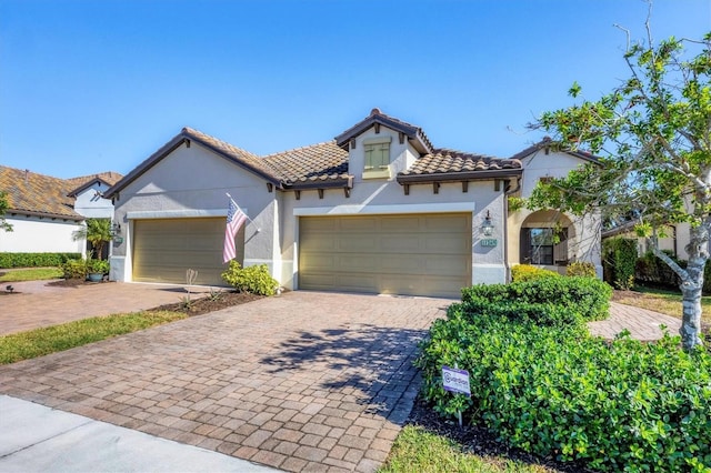 11265 Mc Dermott Ct, Englewood, FL 34223 - mediterranean / spanish home featuring an attached garage, stucco siding, decorative driveway, and a tile roof