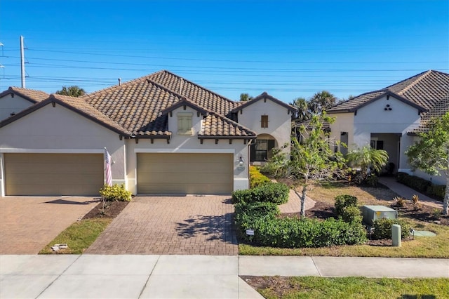 11265 Mc Dermott Ct, Englewood, FL 34223 - mediterranean / spanish house featuring a garage, decorative driveway, a tile roof, and stucco siding