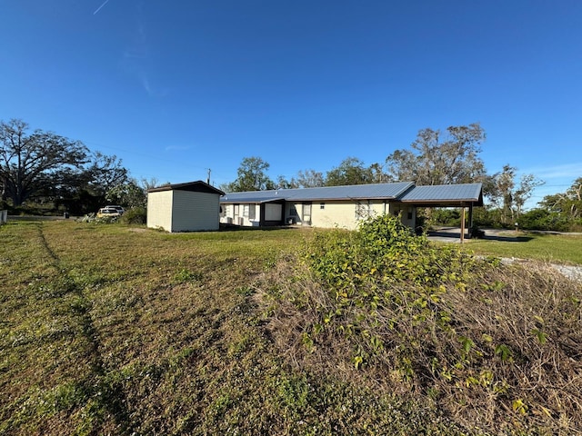 view of front of home featuring a front lawn, a storage unit, and a carport