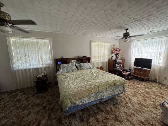 bedroom featuring ceiling fan, dark carpet, and a textured ceiling