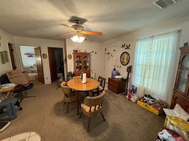 dining area featuring a textured ceiling, carpet floors, and ceiling fan