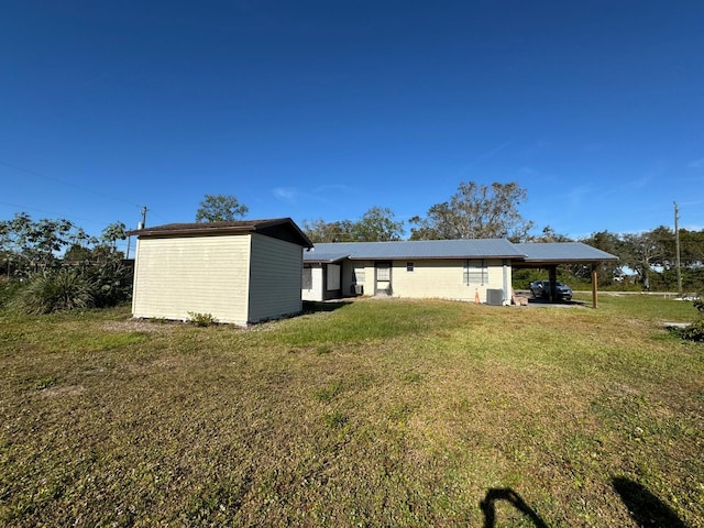 rear view of house featuring central air condition unit, a yard, and a carport