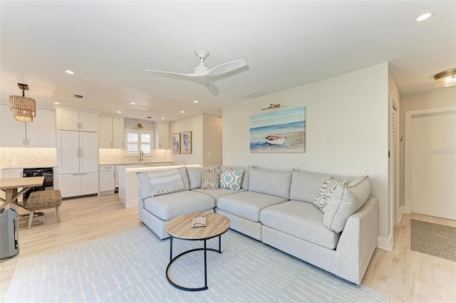 living room with ceiling fan, light wood-type flooring, sink, and wine cooler