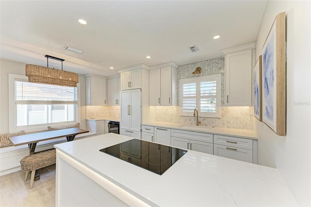 kitchen featuring plenty of natural light, white cabinets, pendant lighting, and white appliances