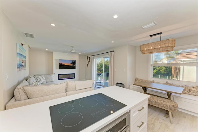 kitchen with white cabinetry, ceiling fan, light hardwood / wood-style flooring, decorative light fixtures, and black electric cooktop